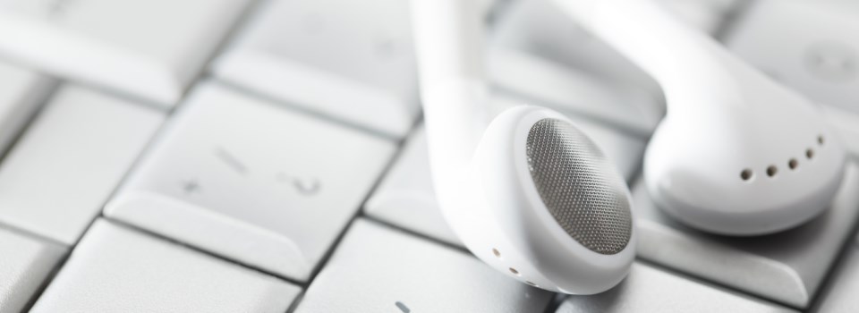 Earphones on top of a keyboard.